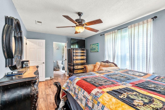 902 S Florey, Mount Pleasant, TX 75455 - bedroom featuring light wood-style floors, a textured ceiling, ensuite bath, and ceiling fan
