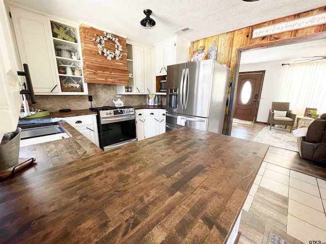 902 S Florey, Mount Pleasant, TX 75455 - kitchen with stainless steel appliances, tasteful backsplash, glass insert cabinets, white cabinetry, and a peninsula