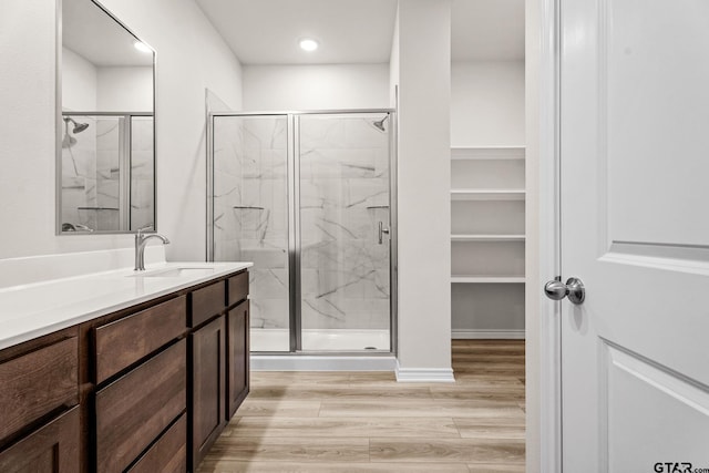 bathroom with hardwood / wood-style floors, vanity, and a shower with shower door