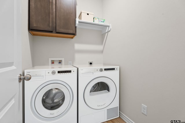 laundry area with washer and dryer and cabinets