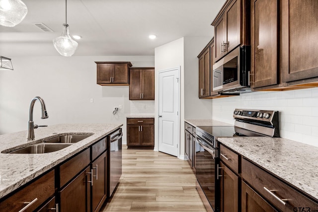 kitchen with dark brown cabinetry, light stone countertops, sink, hanging light fixtures, and stainless steel appliances