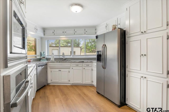 2733 Rockbridge Rd, Tyler, TX 75701 - kitchen featuring appliances with stainless steel finishes, white cabinetry, light stone counters, and light wood-type flooring