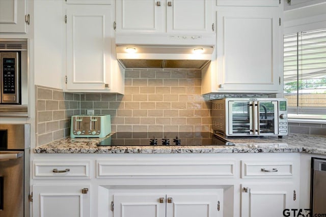2733 Rockbridge Rd, Tyler, TX 75701 - kitchen with appliances with stainless steel finishes, under cabinet range hood, white cabinets, decorative backsplash, and light stone countertops