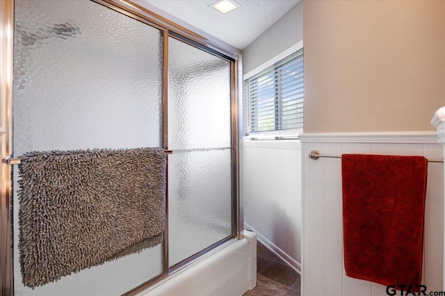 2733 Rockbridge Rd, Tyler, TX 75701 - bathroom featuring combined bath / shower with glass door, a wainscoted wall, and tile patterned flooring