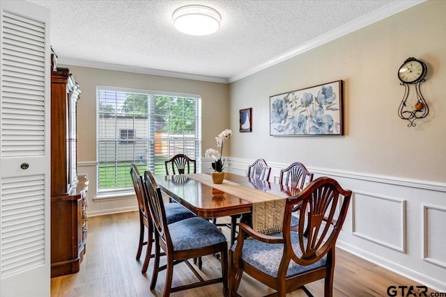 2733 Rockbridge Rd, Tyler, TX 75701 - dining area featuring a textured ceiling, crown molding, wood finished floors, wainscoting, and a decorative wall