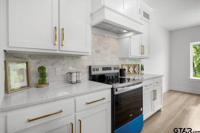 2099 Jackie Ave, Tyler, TX 75703 - kitchen featuring stainless steel electric stove, custom exhaust hood, decorative backsplash, and light wood finished floors