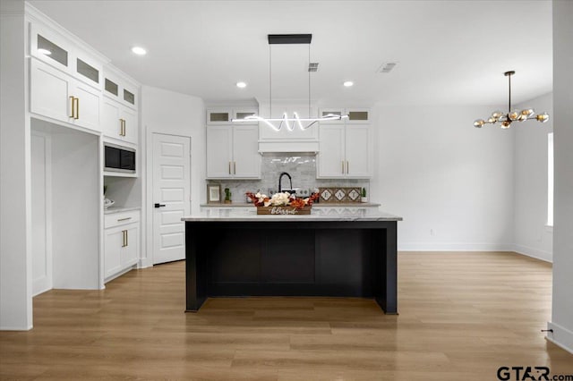 2099 Jackie Ave, Tyler, TX 75703 - kitchen featuring a chandelier, built in microwave, tasteful backsplash, white cabinets, and light wood-style floors