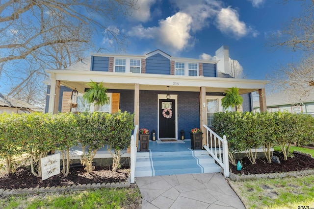 view of front of home with brick siding and covered porch