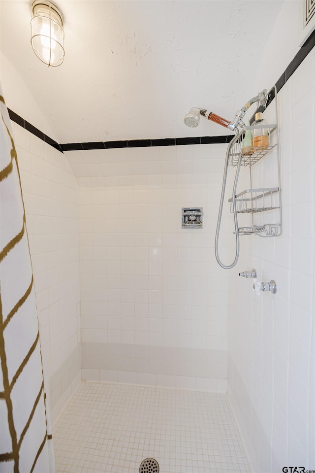 full bath with a tile shower and vaulted ceiling