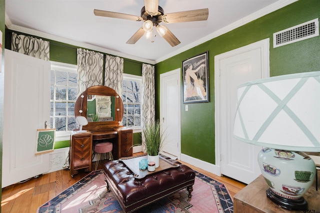 sitting room with wood finished floors, baseboards, visible vents, ceiling fan, and crown molding