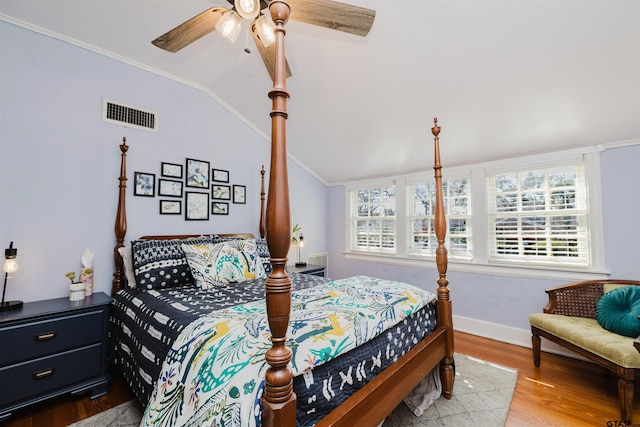 bedroom featuring visible vents, ornamental molding, wood finished floors, baseboards, and vaulted ceiling