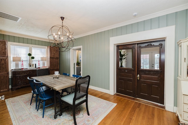 dining space with visible vents, ornamental molding, wood finished floors, baseboards, and a chandelier