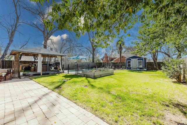 view of yard featuring a fenced backyard, a gazebo, a vegetable garden, an outdoor structure, and a patio area