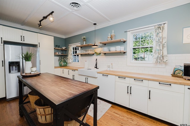 kitchen with light wood finished floors, backsplash, wooden counters, stainless steel refrigerator with ice dispenser, and a sink