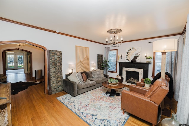 living area with crown molding, plenty of natural light, wood finished floors, and arched walkways