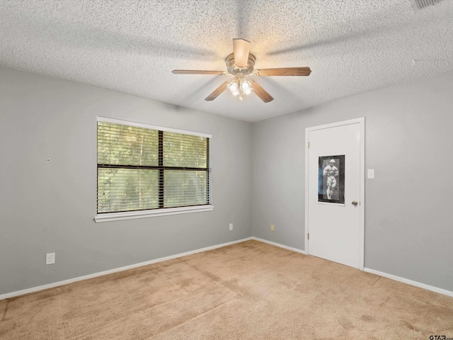 spare room with a textured ceiling, light colored carpet, and ceiling fan