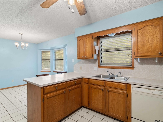 kitchen with a textured ceiling, white dishwasher, hanging light fixtures, sink, and kitchen peninsula