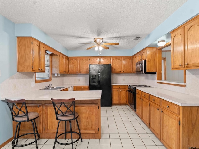 kitchen featuring kitchen peninsula, black appliances, a textured ceiling, a breakfast bar area, and ceiling fan