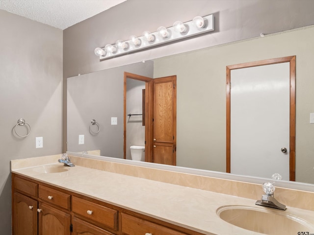 bathroom featuring toilet, vanity, and a textured ceiling