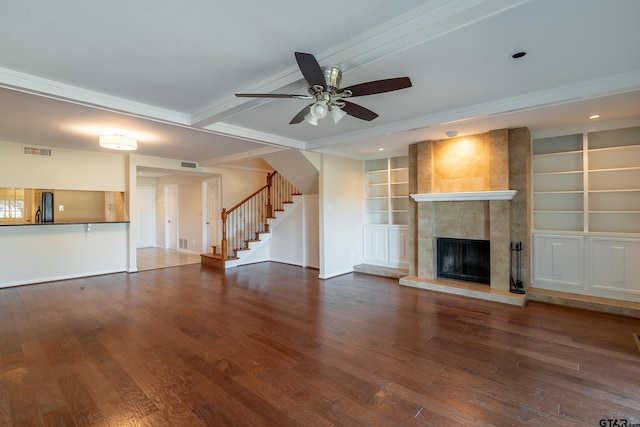 unfurnished living room featuring visible vents, built in features, stairway, a tile fireplace, and wood finished floors