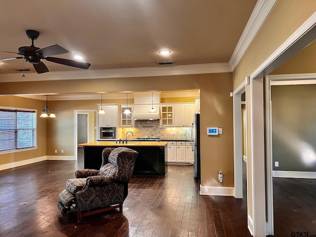 kitchen with stainless steel appliances, decorative light fixtures, a breakfast bar, white cabinets, and a kitchen island with sink