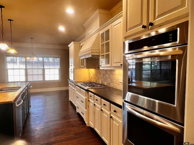 kitchen featuring dark hardwood / wood-style floors, crown molding, backsplash, appliances with stainless steel finishes, and premium range hood