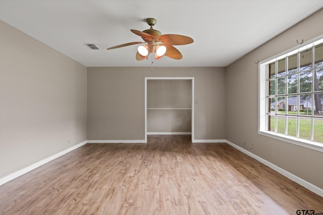 empty room featuring a ceiling fan, baseboards, visible vents, and wood finished floors