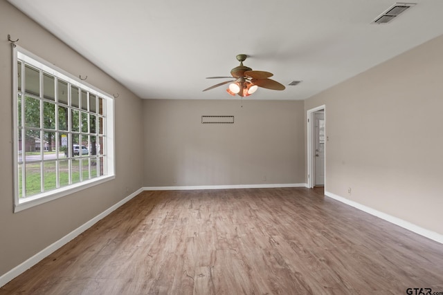 spare room with baseboards, ceiling fan, visible vents, and wood finished floors