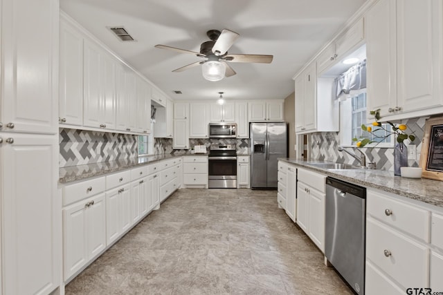 kitchen with visible vents, decorative backsplash, a ceiling fan, a sink, and stainless steel appliances
