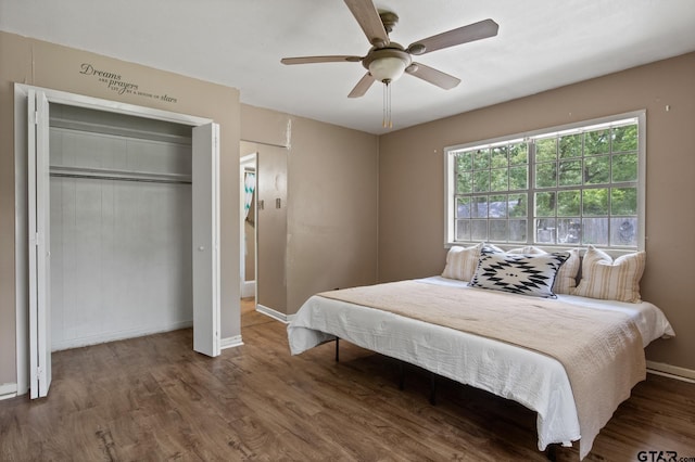 bedroom with baseboards, ceiling fan, wood finished floors, and a closet