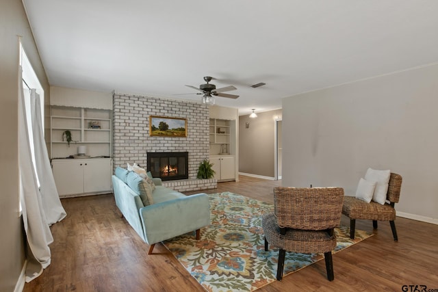 living room with baseboards, ceiling fan, wood finished floors, and a fireplace