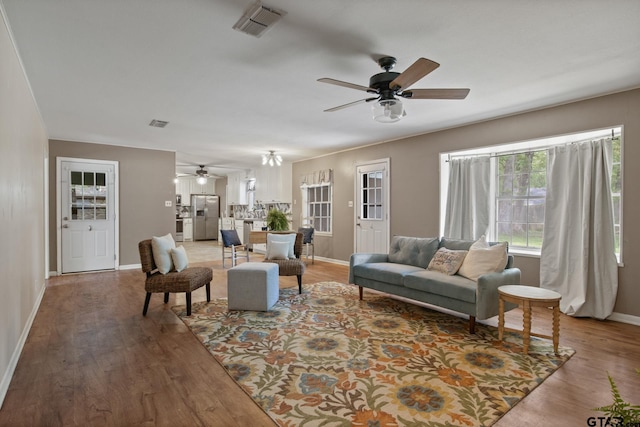 living area with ceiling fan, visible vents, baseboards, and light wood-type flooring