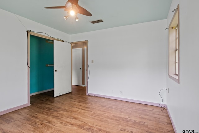unfurnished room featuring baseboards, ceiling fan, wood finished floors, and visible vents