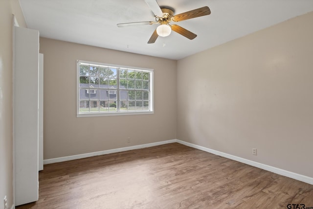 empty room with a ceiling fan, baseboards, and wood finished floors