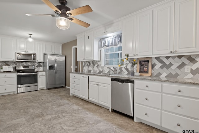 kitchen featuring decorative backsplash, ceiling fan, white cabinets, a sink, and stainless steel appliances