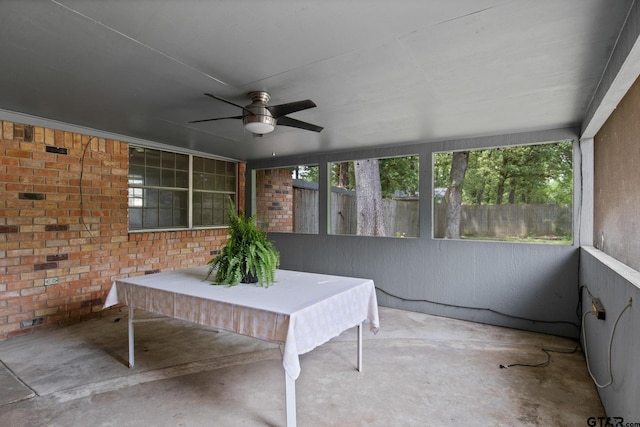 sunroom with ceiling fan and concrete flooring