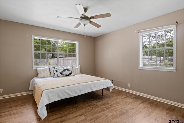 bedroom featuring a ceiling fan, baseboards, and wood finished floors