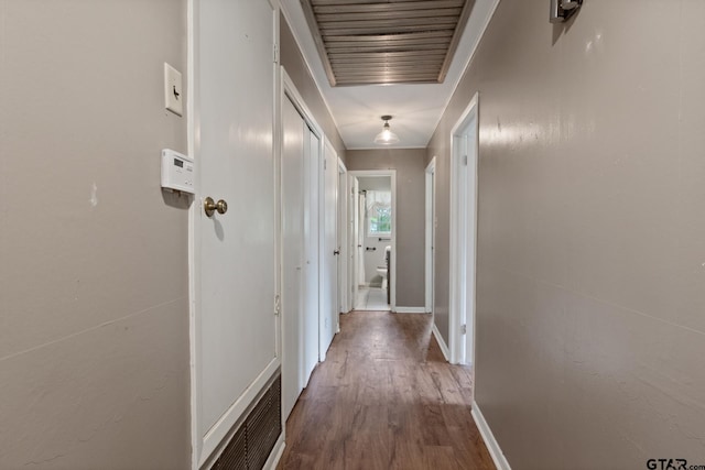 hallway featuring baseboards, wood finished floors, and visible vents