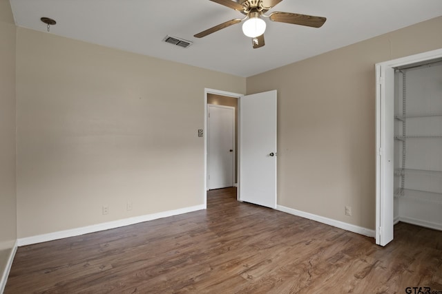 unfurnished bedroom with baseboards, a closet, wood finished floors, and visible vents