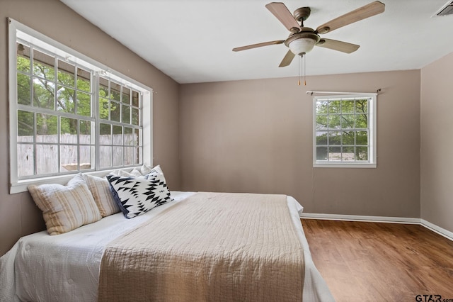bedroom featuring ceiling fan, baseboards, visible vents, and wood finished floors