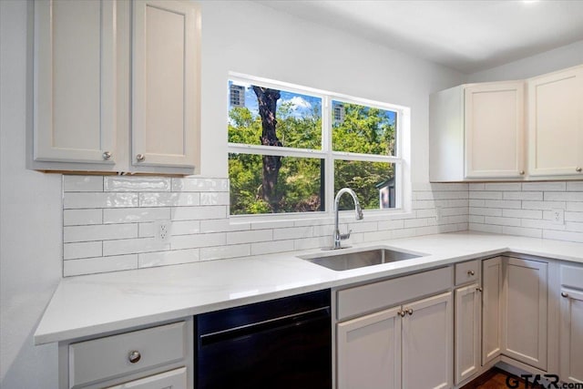 kitchen with black dishwasher, tasteful backsplash, and a sink