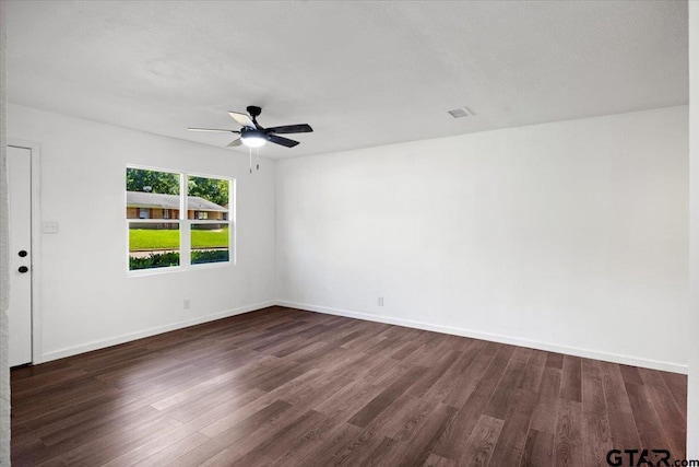 spare room featuring a ceiling fan, baseboards, and dark wood-style flooring