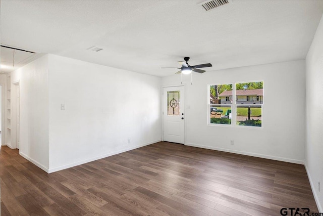 empty room featuring attic access, wood finished floors, visible vents, and ceiling fan