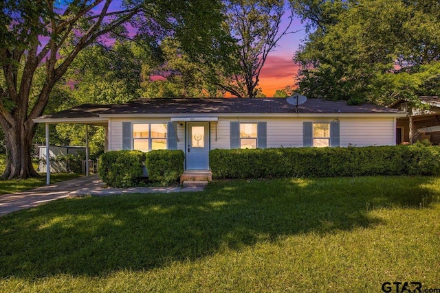 ranch-style home with entry steps, a lawn, an attached carport, and concrete driveway
