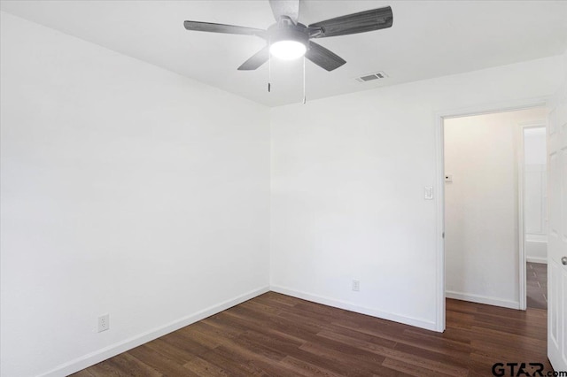 spare room featuring a ceiling fan, baseboards, dark wood-style flooring, and visible vents
