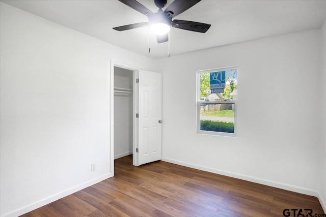 unfurnished bedroom with ceiling fan, baseboards, dark wood-style flooring, and a closet