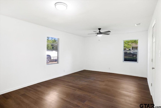 unfurnished room featuring a wealth of natural light, a ceiling fan, dark wood-type flooring, and visible vents