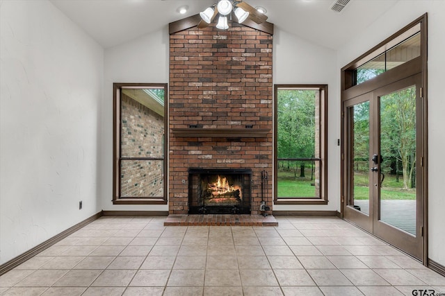 unfurnished living room with a brick fireplace, light tile patterned flooring, and lofted ceiling