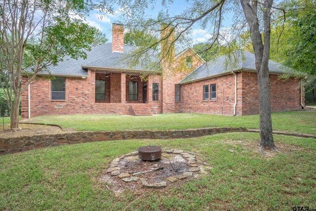 4601 Dickens, Athens, TX 75751 - back of property with a fire pit, brick siding, a chimney, and a lawn