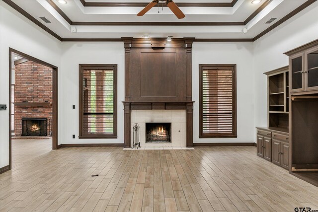 4601 Dickens, Athens, TX 75751 - unfurnished living room with a large fireplace, ceiling fan, a tray ceiling, crown molding, and light wood-type flooring